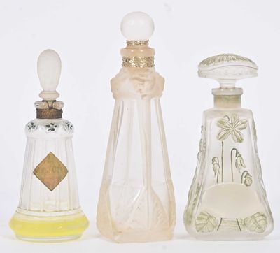 Trois types différents de flacons de parfum sont alignés sur une surface blanche