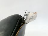 une petite souris blanche assise sur une chaise noire
