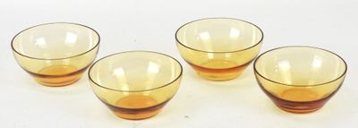 quatre verres jaunes posés sur une surface blanche