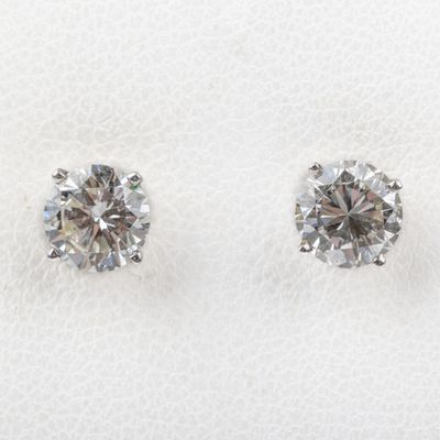 a pair of diamond earrings sitting on top of a white cloth