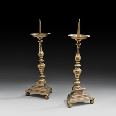 une paire de bougeoirs en laiton montés sur des supports à roulettes