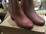 une paire de bottines en cuir marron posée sur une boîte en carton
