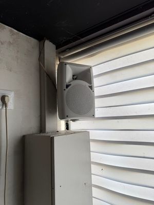 a white box with a speaker on top of it next to a window
