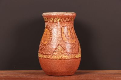 un vase marron posé sur une table, avec un mur noir en arrière-plan