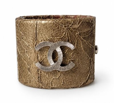 a close up of a gold bracelet with a chanel logo on it