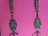 two silver necklaces on a pink background with a chain around them