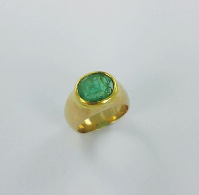 gros plan d'une bague en or avec une pierre verte