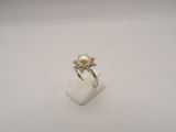 une image d'une bague en perles et diamants sur une surface blanche