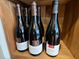 Plusieurs bouteilles de vin sont posées sur une étagère en bois dans un magasin