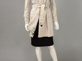 un mannequin vêtu d'un trench-coat beige et d'une jupe noire
