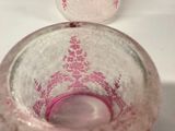 a glass with a pink design on it sitting on a table