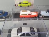 four toy cars in a display case on a table