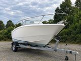 a white boat on a trailer parked in a parking lot