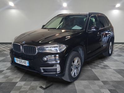 the bmw x5 is parked in a large room with a checkered floor