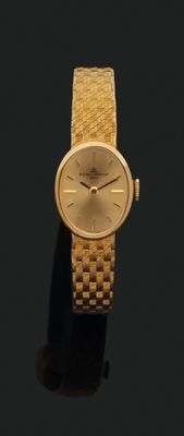une photo d'une montre-bracelet dorée posée sur une surface noire