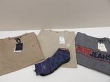 trois t-shirts pour homme et une paire de chaussettes posés sur une table