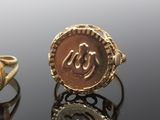two gold rings with arabic calligraphys on them on a reflective surface