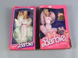 two barbie dolls are sitting in a pink box on a table