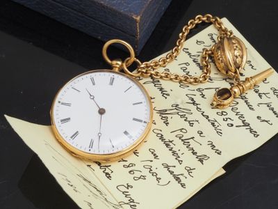 une montre de poche en or posée sur un morceau de papier