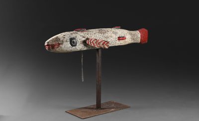 une sculpture en bois représentant un poisson, posée sur un socle en métal