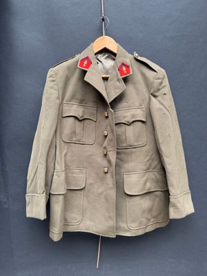 une vieille veste militaire suspendue à un cintre devant un mur bleu