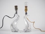 two clear glass lamps with a gold cord on a white surface