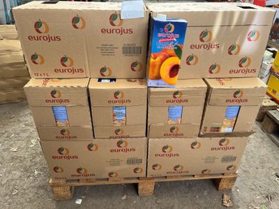 Plusieurs caisses d'oranges sont empilées sur une palette dans un entrepôt
