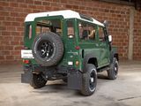 a green and white jeep parked in front of a brick wall