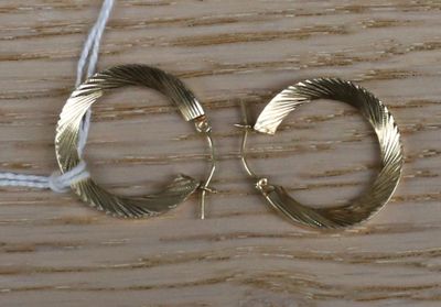une paire de boucles d'oreilles créoles en or posée sur une table