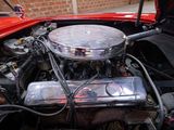 a red car with a chrome engine in the trunk