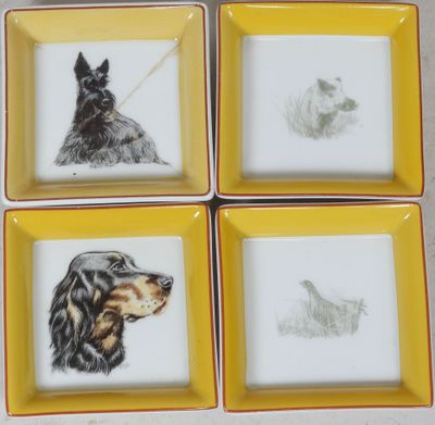 four square plates with dogs drawn on them on a table