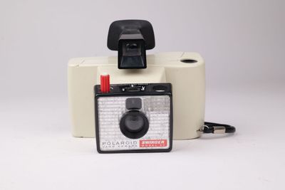 un appareil photo Polaroid et un rouleau de papier toilette posés sur une surface blanche