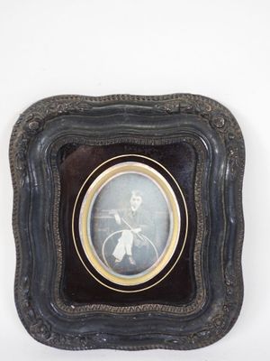 an old picture of a man riding a bicycle in a black frame