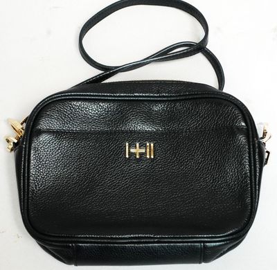 un sac à bandoulière noir sur lequel figure la lettre « h »