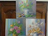 trois tableaux représentant des fleurs dans un vase posé sur une table en bois