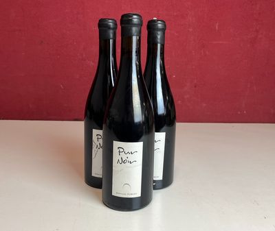 trois bouteilles de vin sont posées sur un comptoir devant un mur rouge