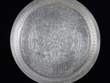 une vieille assiette en argent ornée d'un motif sur fond noir