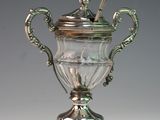 a silver vase with a spoon on top of it