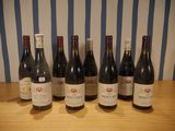six bottles of wine are lined up on a wooden table