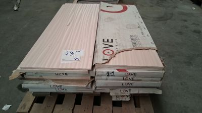 plusieurs piles de planches de bois empilées sur une palette dans un entrepôt