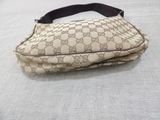 beige and black guccissi bag on a bed with white sheets