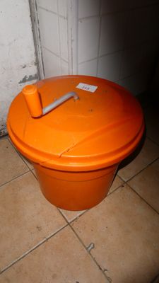 une poubelle orange posée par terre dans une salle de bains