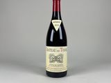 a bottle of red wine sitting on top of a white table