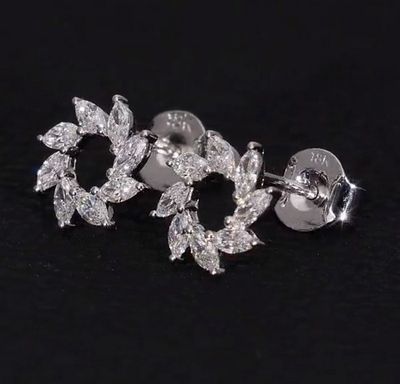 un gros plan sur une paire de boucles d'oreilles en diamant posées sur une surface noire