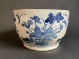 a blue and white bowl with flowers and leaves on it