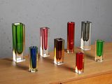 many different colored glass vases sitting on a wooden table