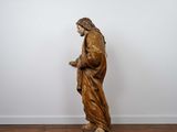 a statue of jesus standing on a wooden floor in front of a white wall