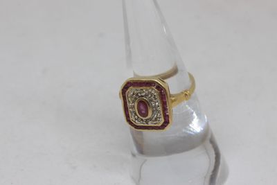 a gold ring with a red stone on top of a clear glass