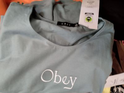 a blue shirt with the word obey on it next to other items