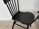 a black chair sitting next to a white wall